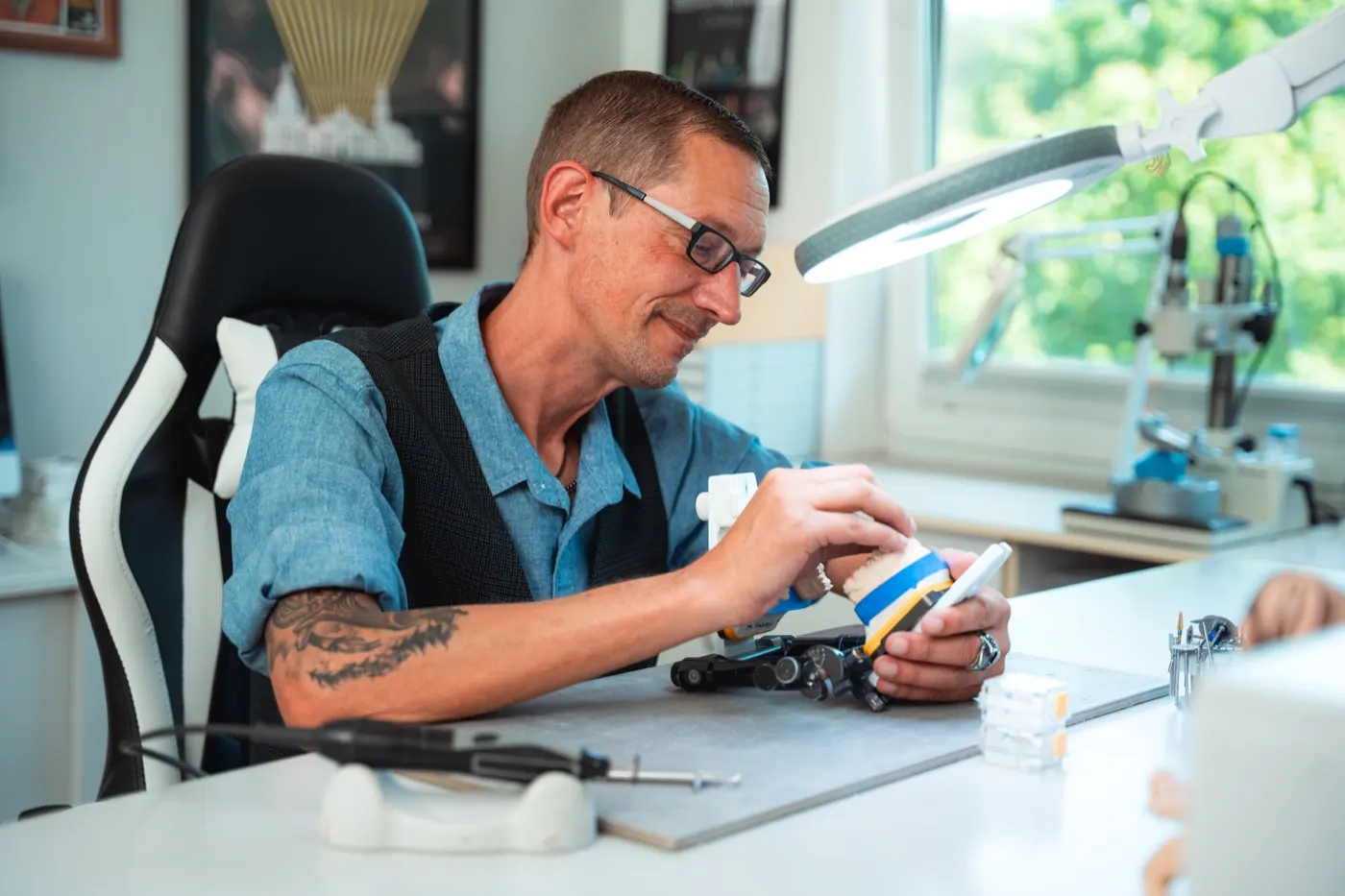 Zahntechniker bei der Feinarbeit unter der Lupenleuchte
